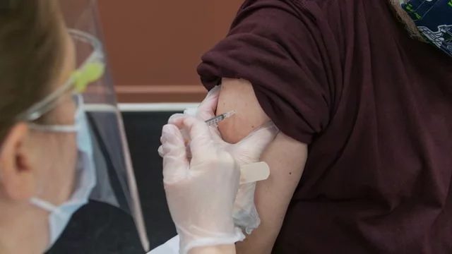 The image shows a health care worker administering the SARS-CoV-2 vaccine to a patient. Reinfection likely without vaccination. Originally taken from https://www.technologynetworks.com/biopharma/news/sars-cov-2-reinfection-likely-without-vaccination-354368.